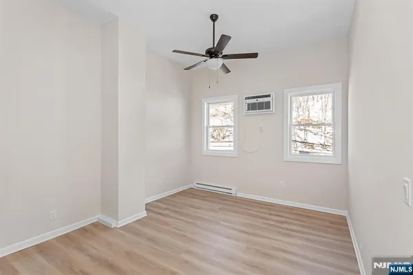 an empty room with wooden floor ceiling fan and windows