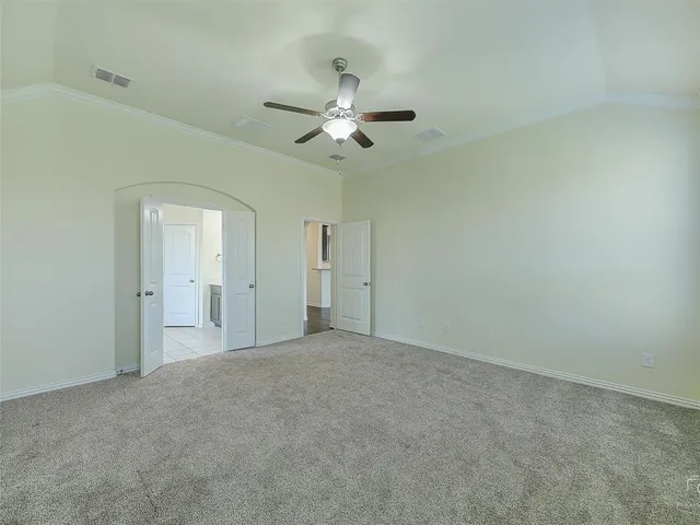 an empty room with chandelier fan and windows