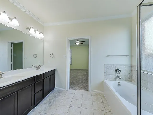 a bathroom with a tub a double vanity sink and mirror