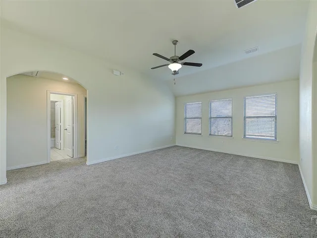 an empty room with windows and ceiling fan