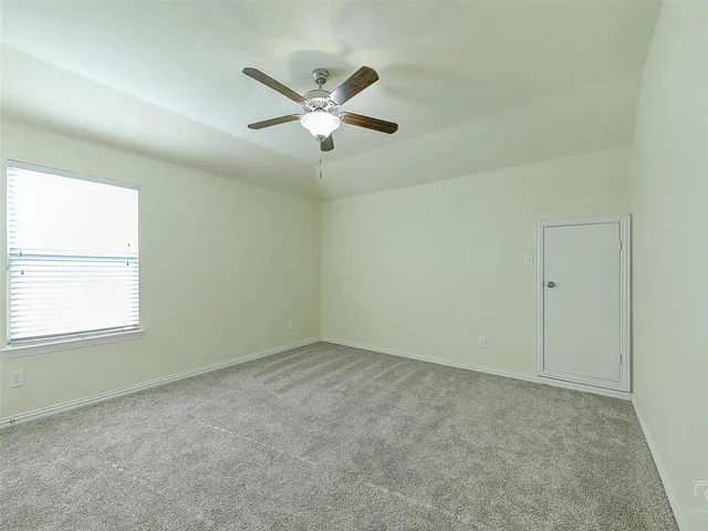 an empty room with a window and a fan