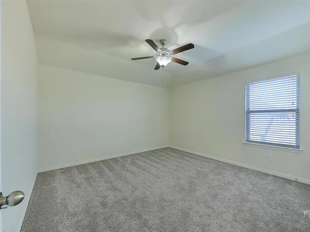 an empty room with a window and a fan