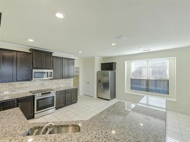 a large kitchen with stainless steel appliances granite countertop a sink stove and refrigerator