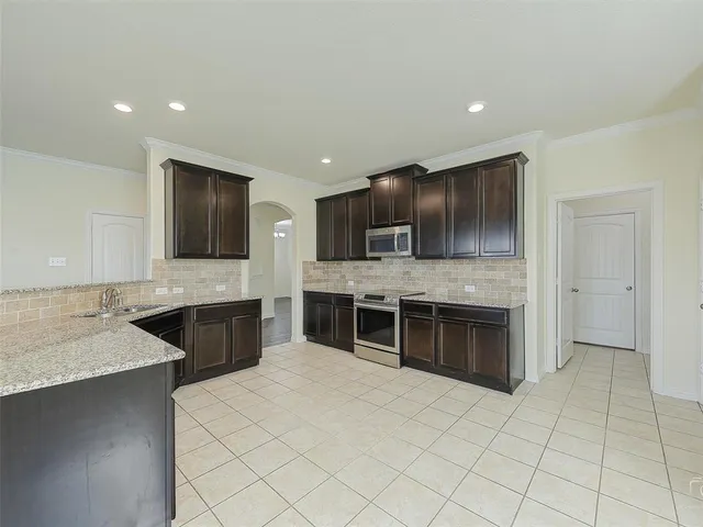 a large kitchen with a large counter top stainless steel appliances and cabinets