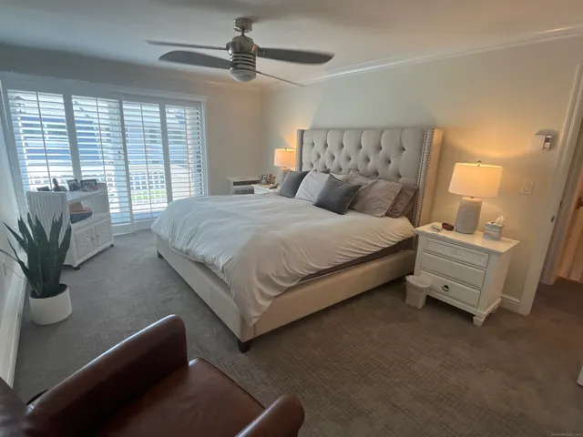 a bedroom with a large bed and a chandelier fan