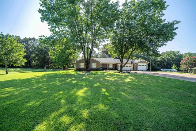 a front view of a house with garden and a tree