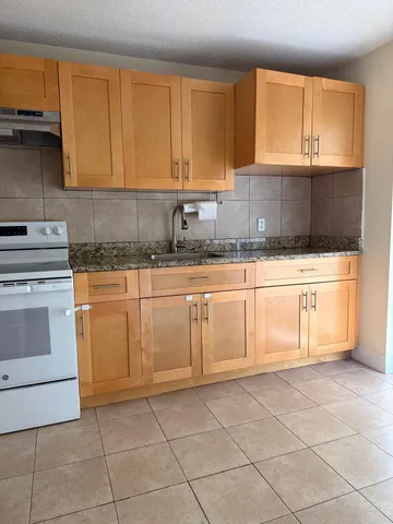 a kitchen with granite countertop a sink a stove and cabinets