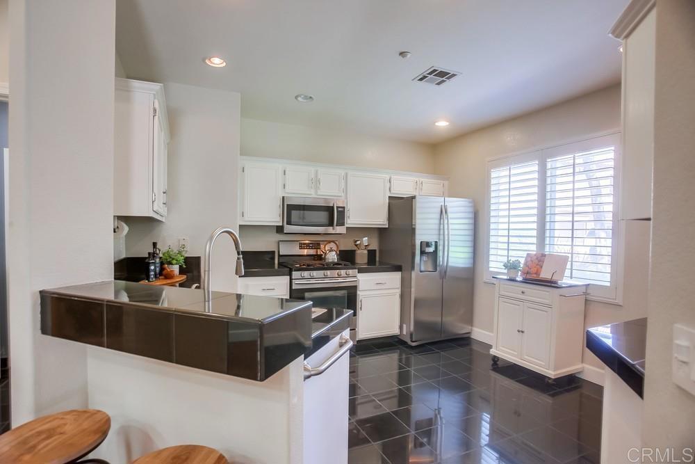 6094 Citracado Circle Carlsbad, CA 92009 - Photo 13 of 47 a kitchen with stainless steel appliances kitchen island granite countertop a refrigerator stove microwave and sink