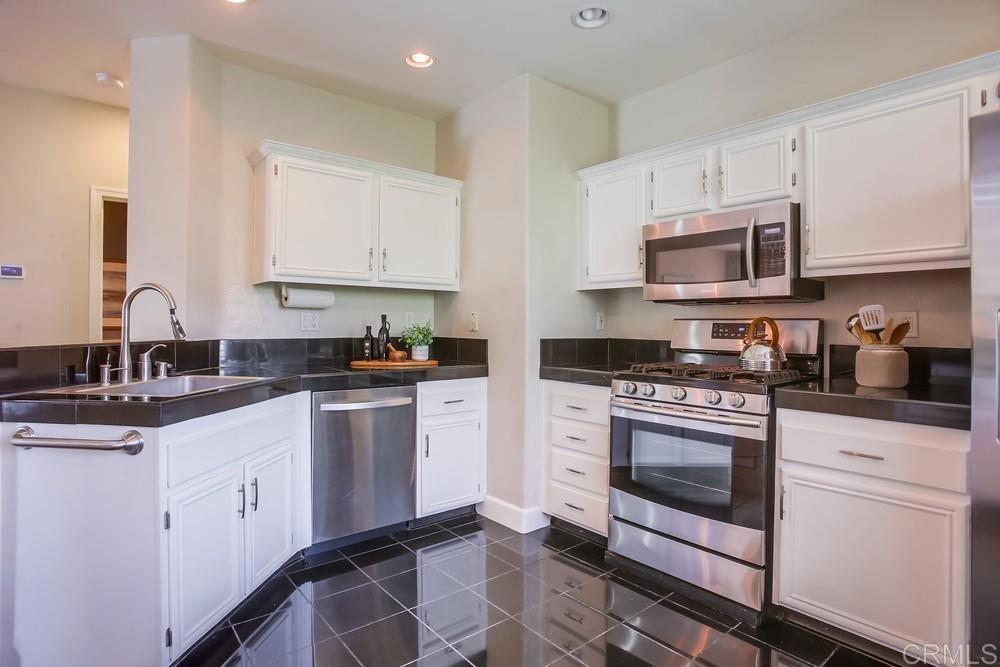 6094 Citracado Circle Carlsbad, CA 92009 - Photo 15 of 47 a kitchen with granite countertop white cabinets sink and stainless steel appliances