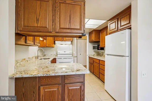 a kitchen with granite countertop stainless steel appliances a refrigerator and cabinets