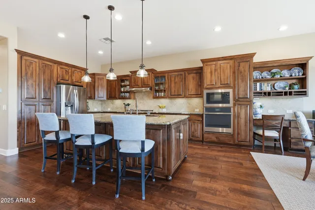 a kitchen with stainless steel appliances granite countertop a sink a stove and a wooden floors