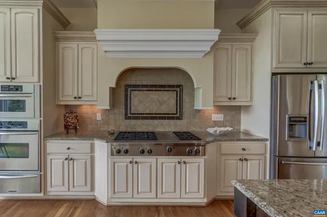 a kitchen with stainless steel appliances granite countertop a stove and a wooden floors