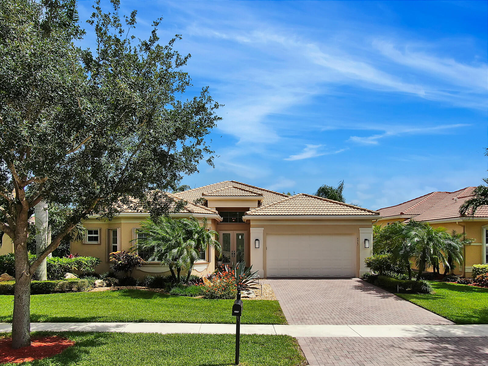 6967 Corning Circle Boynton Beach, FL 33437 - Photo 42 of 62 a front view of a house with a garden and trees