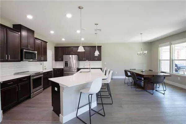 a kitchen with stainless steel appliances kitchen island granite countertop a sink a stove a dining table and chairs