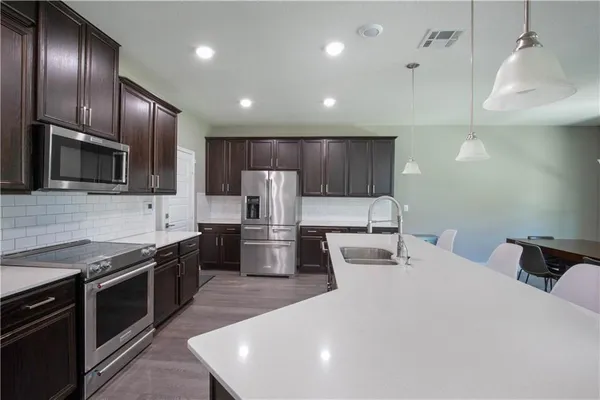 a kitchen with granite countertop stainless steel appliances a sink stove and refrigerator