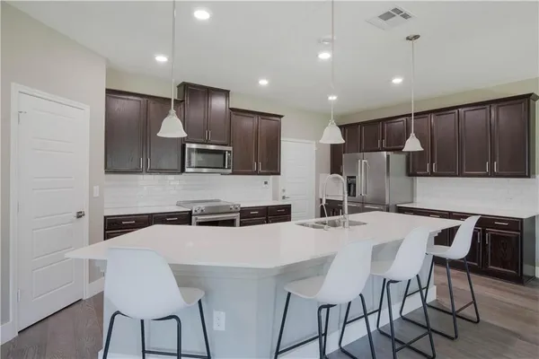 a kitchen with stainless steel appliances a table chairs refrigerator and microwave