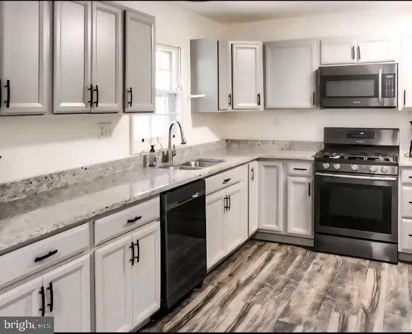 a kitchen with granite countertop a stove top oven microwave and cabinets