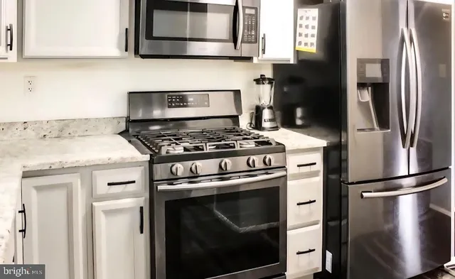 a kitchen with stainless steel appliances granite countertop a stove a refrigerator and a microwave