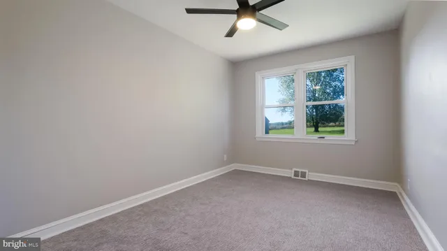 an empty room with a window and a fan