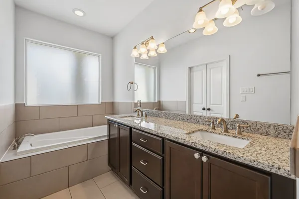 a bathroom with a granite countertop sink a large mirror and a bathtub