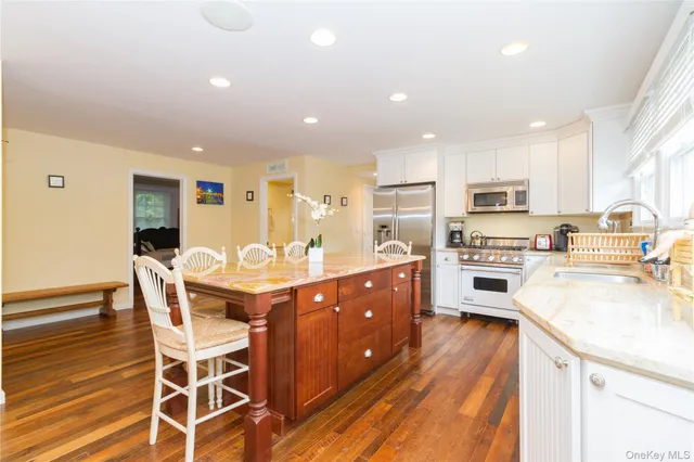a kitchen with stainless steel appliances kitchen island granite countertop a table chairs sink and cabinets