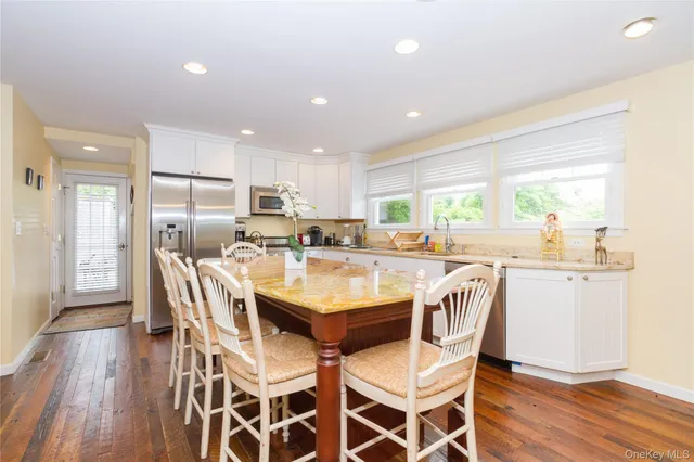 a kitchen with a dining table chairs wooden floor cabinets and stainless steel appliances