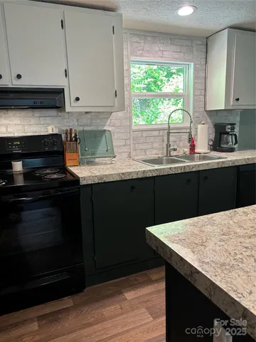 a kitchen with granite countertop cabinets stove and sink