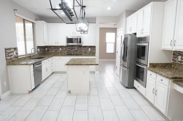 a kitchen with stainless steel appliances granite countertop a sink a stove a refrigerator and cabinets