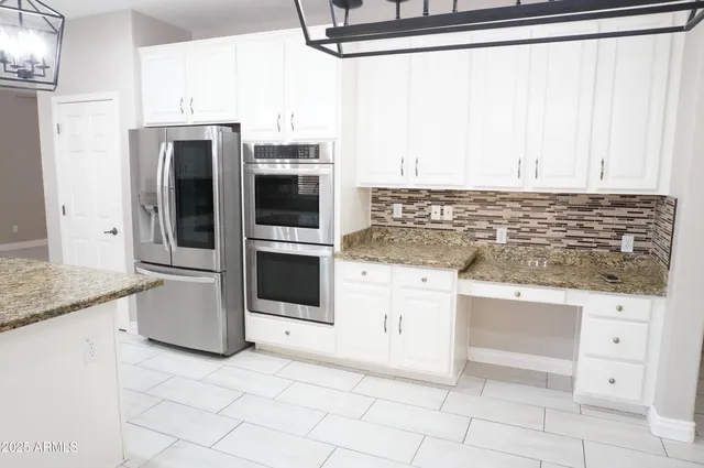 a kitchen with granite countertop a refrigerator sink stove and oven