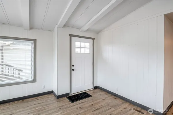 a view of an empty room with wooden floor and a window
