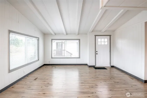 a view of an empty room with wooden floor and a window