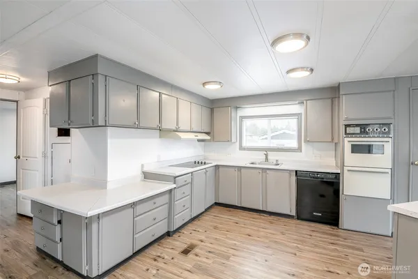 a large kitchen with cabinets wooden floor and stainless steel appliances