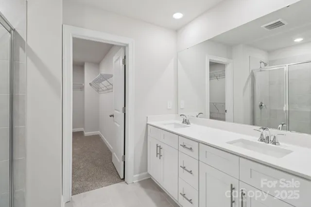a bathroom with a double vanity sink and mirror with shower