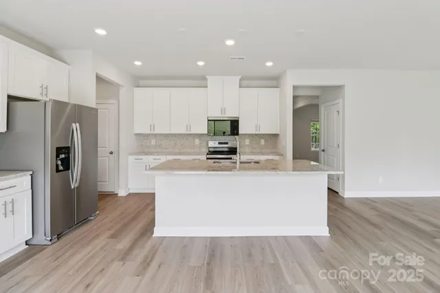 a large kitchen with stainless steel appliances a large counter top a refrigerator and a stove