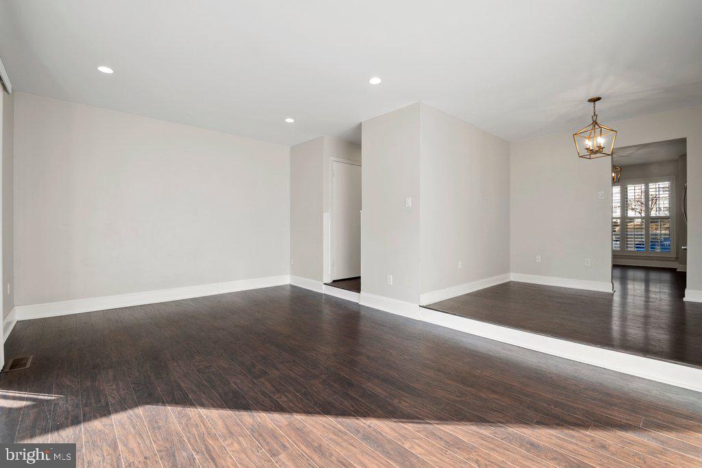 7472 Setting Sun Way Columbia, MD 21046 - Photo 13 of 40 a view of an empty room with wooden floor and a kitchen