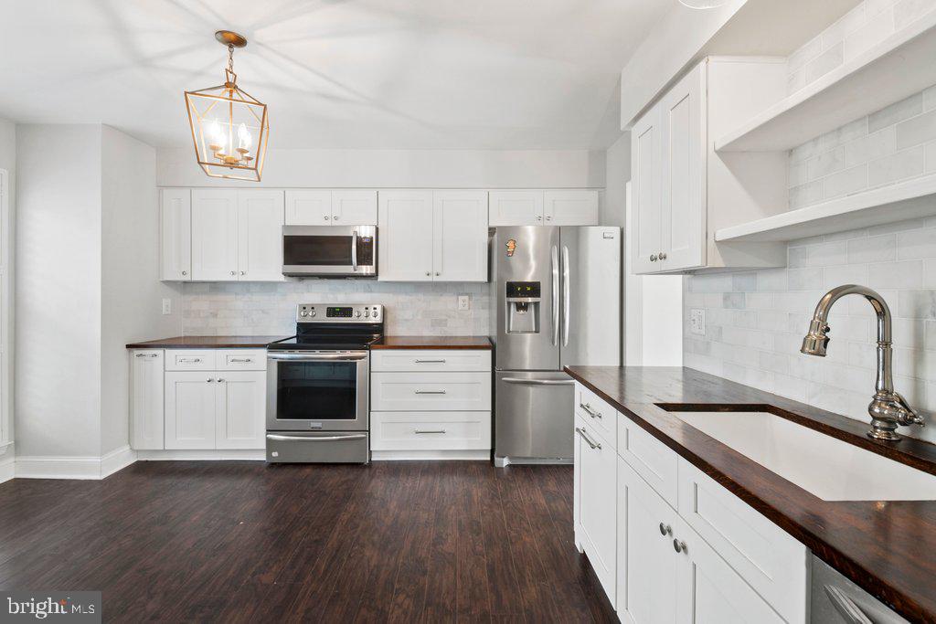 7472 Setting Sun Way Columbia, MD 21046 - Photo 6 of 40 a kitchen with granite countertop white cabinets and stainless steel appliances