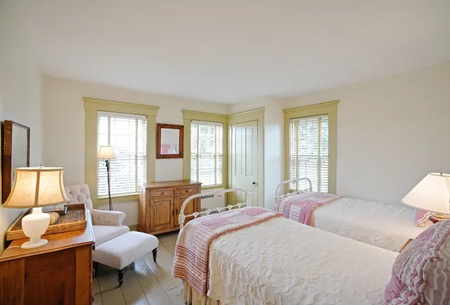 a bedroom with two beds and large windows