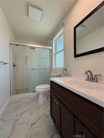 a bathroom with a granite countertop sink toilet a mirror and shower