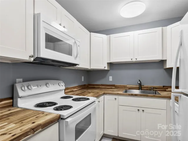 a kitchen with granite countertop white cabinets and white appliances