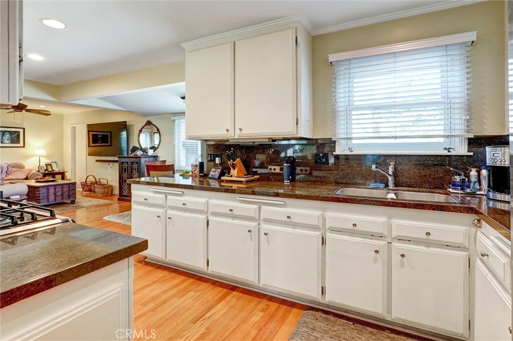 6649 Ranchito Avenue Van Nuys, CA 91405 - Photo 12 of 31 a kitchen with granite countertop white cabinets sink and a large window
