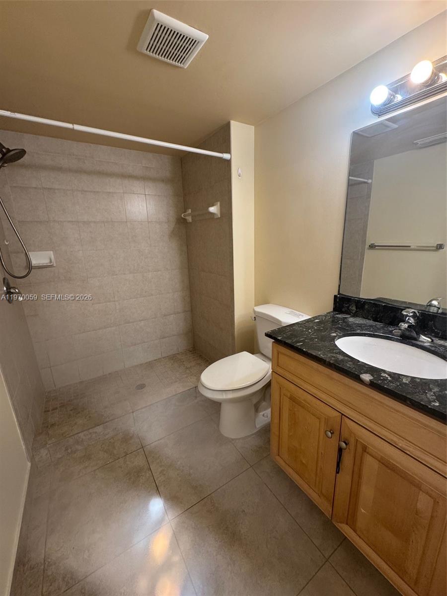 9001 Wiles Road, Unit 204 Coral Springs, FL 33067 - Photo 12 of 16 a bathroom with a granite countertop sink toilet and shower