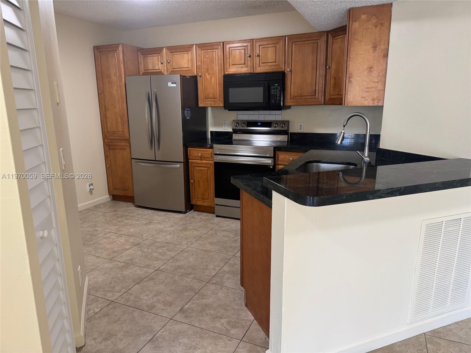 9001 Wiles Road, Unit 204 Coral Springs, FL 33067 - Photo 9 of 16 a kitchen with a refrigerator stove and microwave