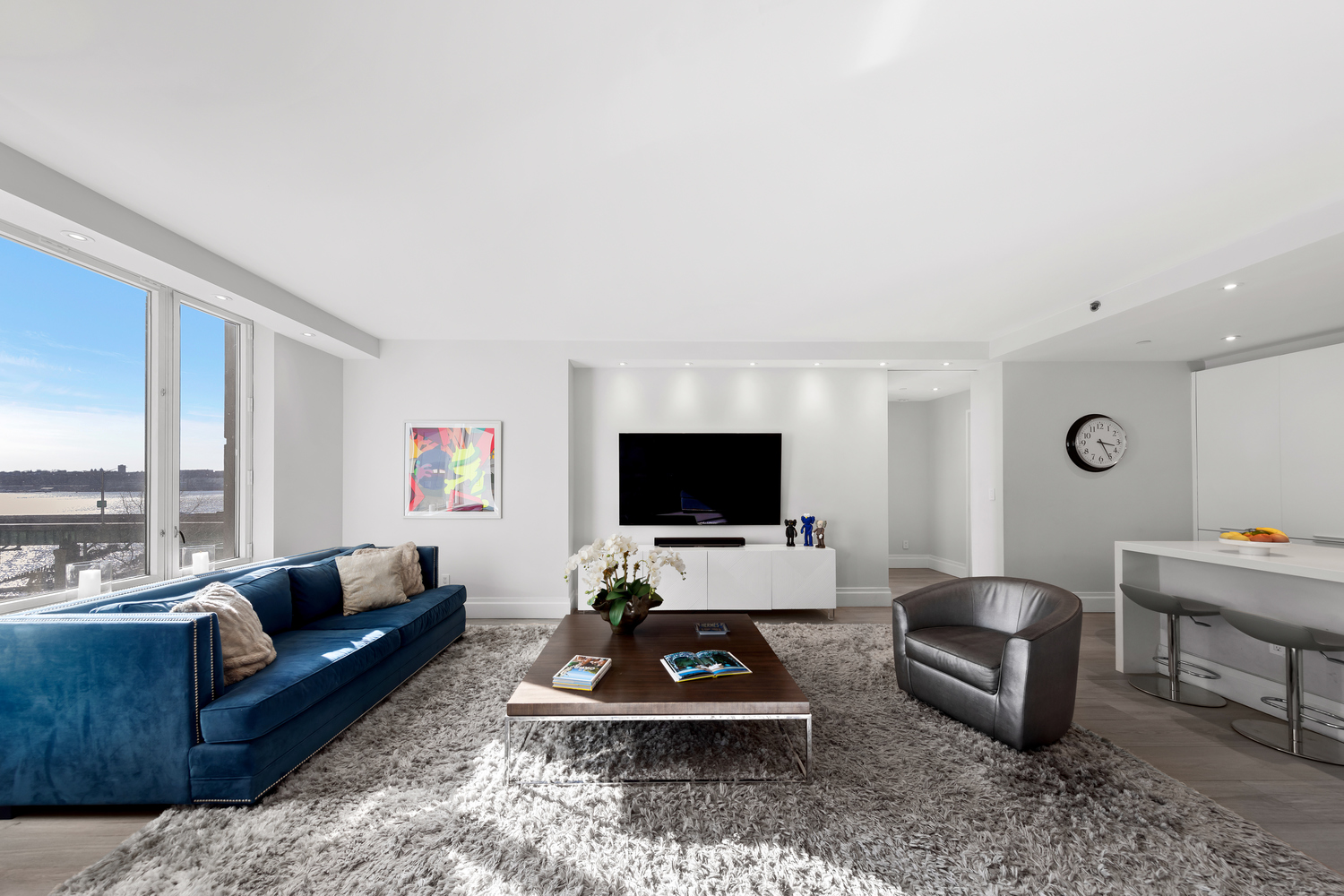 a living room with furniture a rug a large window and a flat screen tv