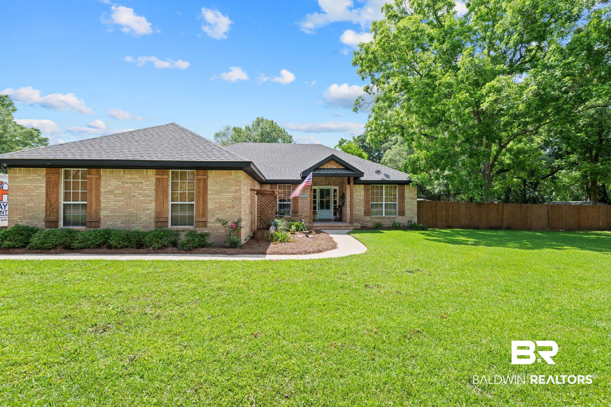 5936 Lundy Road Theodore, AL 36582 - Photo 23 of 32 Brick exterior with a dark-shingle roof, featuring decorative wooden window shutters and a curved concrete walkway