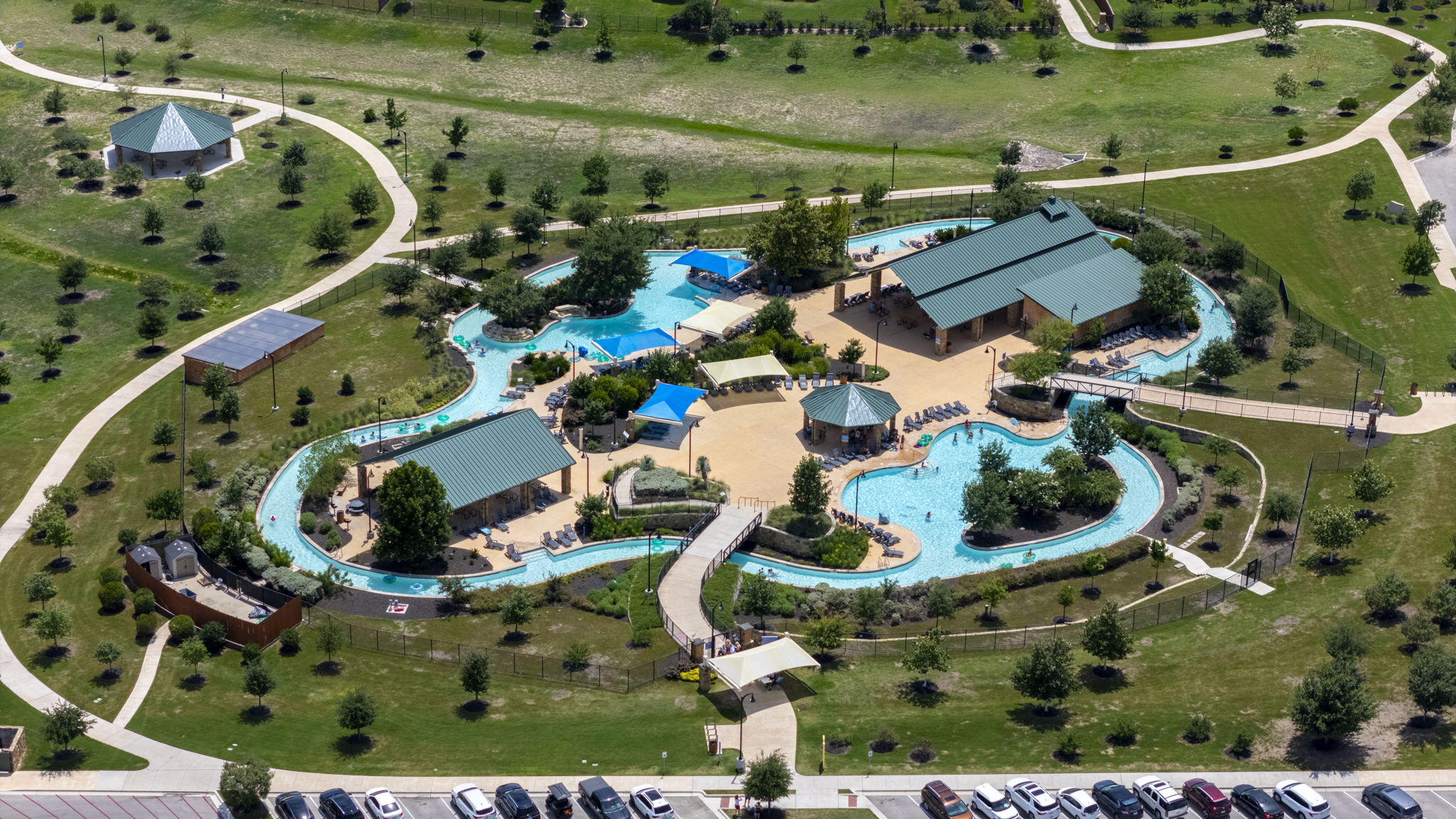 548 Purple Heart Drive Buda, TX 78610 - Photo 32 of 35 An aerial view captures the vibrant community amenities, including a winding pool and recreational facilities, nestled within a landscaped setting.