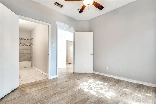 an empty room with wooden floor a ceiling fan and windows