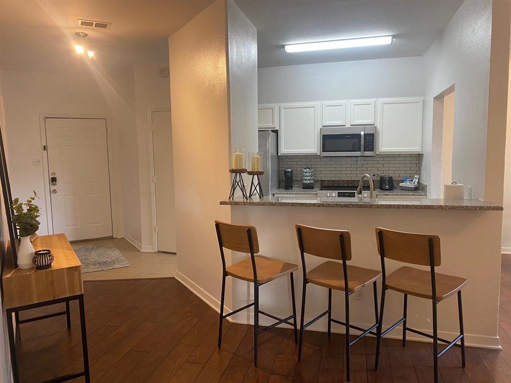 2815 Reagan Street Dallas, TX 75219 - Photo 35 of 40 a kitchen with stainless steel appliances kitchen island granite countertop a sink and cabinets