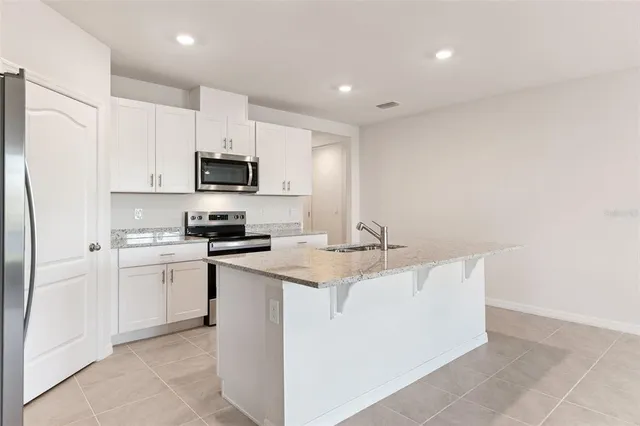 a kitchen with stainless steel appliances a sink a stove a refrigerator a microwave and cabinets