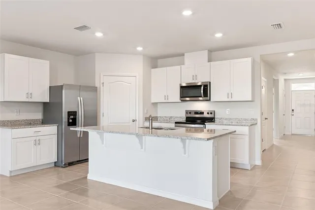 a kitchen with stainless steel appliances granite countertop grey cabinets a refrigerator and a stove
