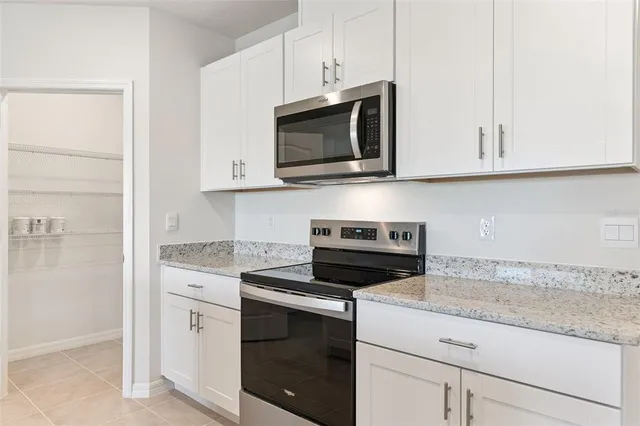 a kitchen with stainless steel appliances granite countertop white cabinets and a stove a sink